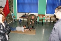 Żołnierz instruuje ucznia jak należy trzymać karabin.