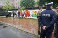 Policjant przygląda się wykonanym pracom graffiti.