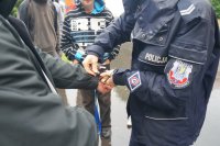 Policjantka demonstruje uczniom zakładanie kajdanek na ręce z przodu.
