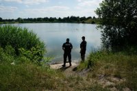 Policjant i Strażnik Miejski obserwują rejon akwenu wodnego