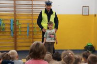 Policjant objaśnia chłopcu zasady bezpieczeństwa na drodze