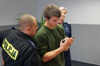 Policjant udziela instrukcji uczniowi przy rozkładaniu pistoletu