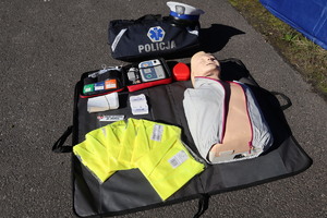 Na zdjęciu widzimy fantom, AED, kamizelki odblaskowe i ulotki oraz torbę medyczną z napisem Policja.