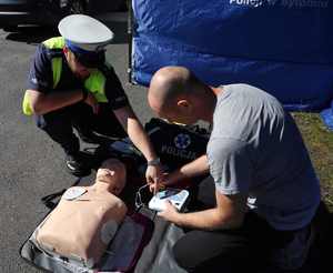Na zdjęciu widzimy, jak policjant tłumaczy mężczyźnie jak przykleić elektrody AED na fantom.