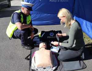 Na zdjęciu kobieta przykleja elektrody z AED na fantom obserwuje ją policjant.