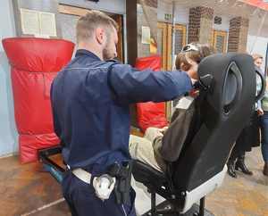 Policjant przy symulatorze zderzeń, na którym znajduje się uczeń.
