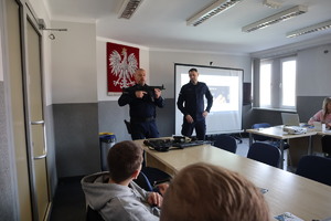 dwaj policjanci w mundurach prezentujący broń uczniom klasy mundurowej w sali konferencyjnej KMP w Bytomiu