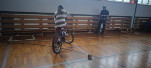 Na zdjęciu uczestniczka na rowerze, obok policjant
